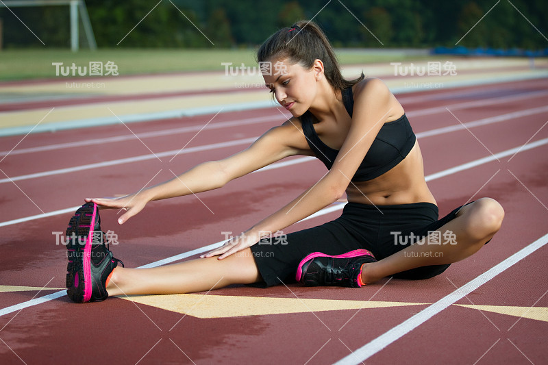 健身女人伸展在一个轨道与模糊的背景