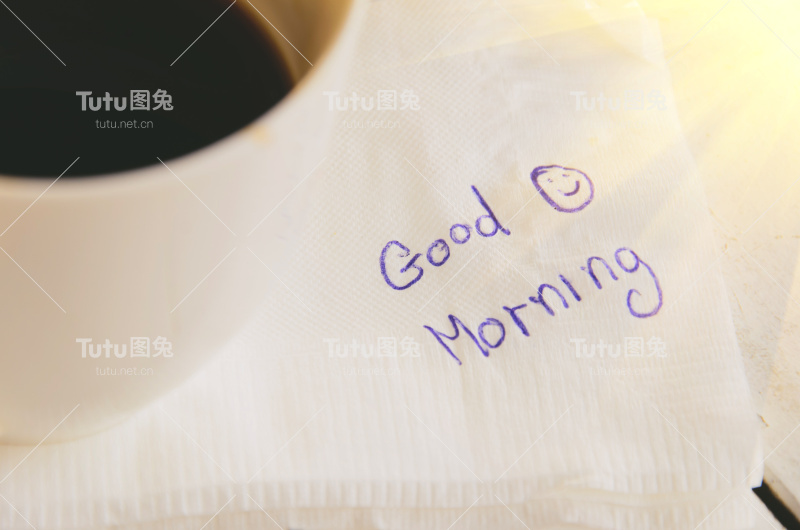 一杯咖啡，一支写着“早上好”的笔