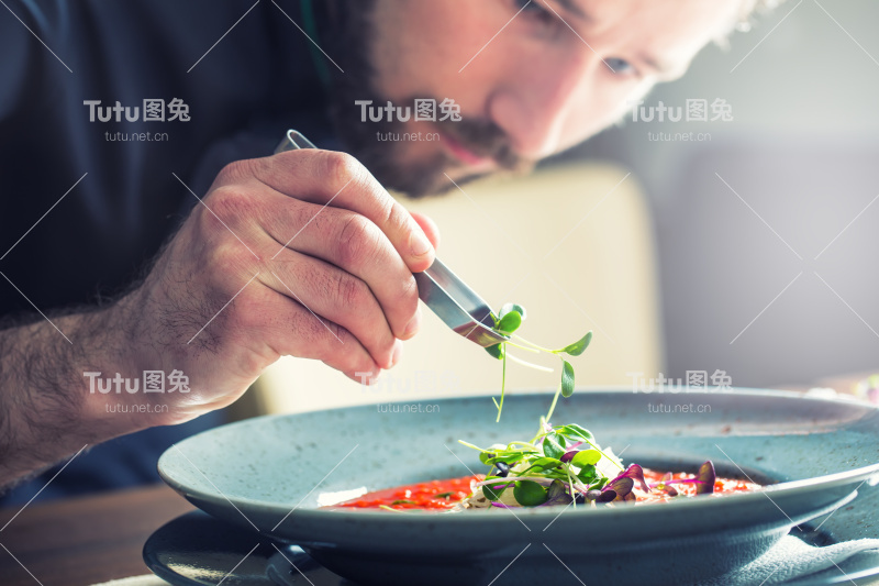 厨师在酒店餐厅厨房做饭，只用手。准备番茄汤