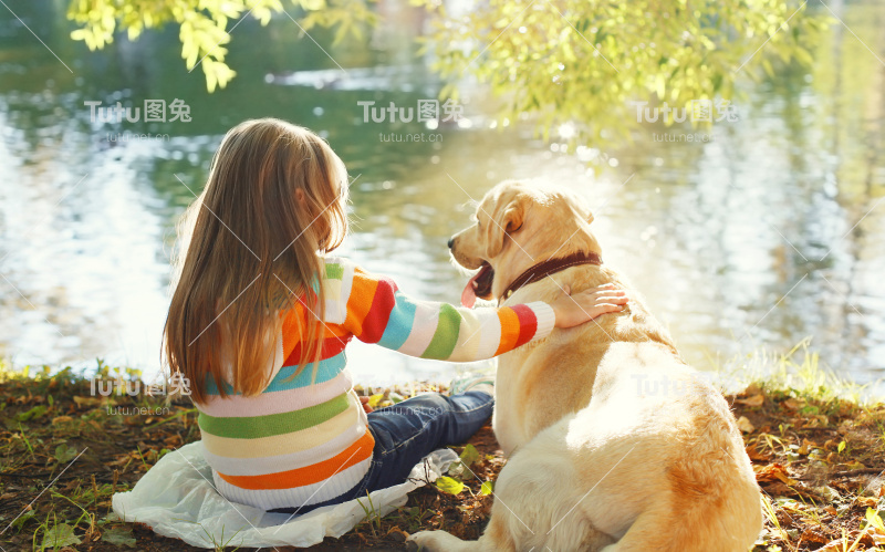 两个朋友，孩子和拉布拉多猎犬坐在阳光下