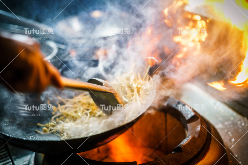 厨师在餐厅厨房的炉子上燃烧着熊熊的火焰