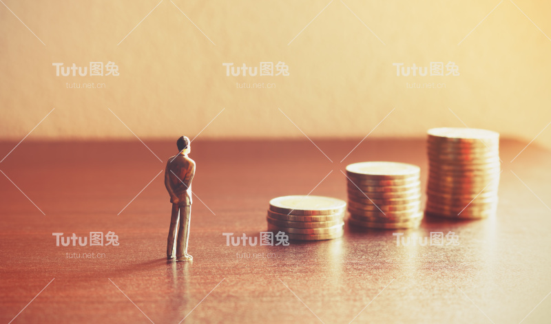 微型的人们展望未来用硬币堆砌关于理财和储蓄的概念。