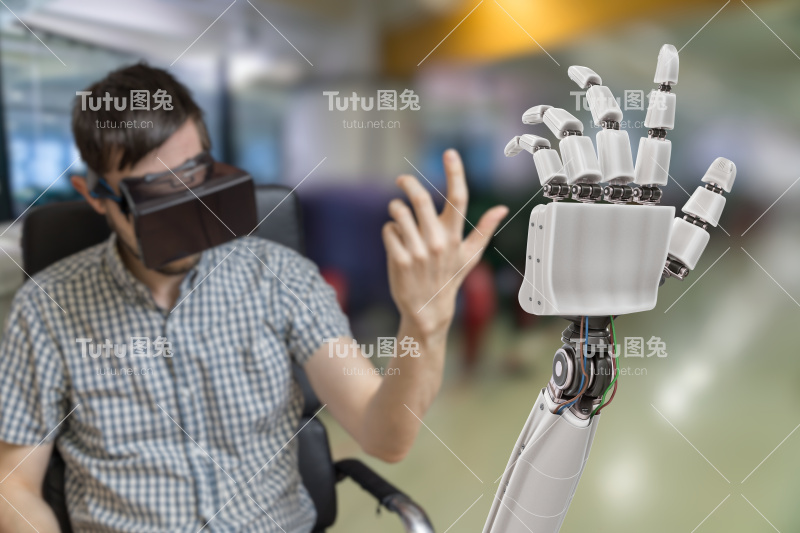 年轻人正在用虚拟现实头盔控制机械手。