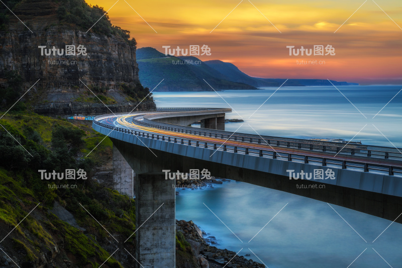 日落在海上悬崖桥沿澳大利亚太平洋海岸与过往的汽车灯光