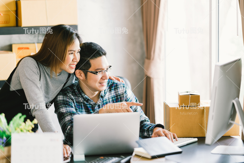 年轻的亚洲夫妇创业家族企业，在线营销包装配送场景。中小企业企业家，商业伙伴，或自由职业者在家工作的概念