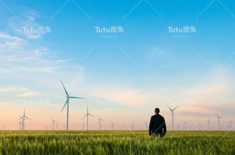 人们在绿色的麦田里用风车发电