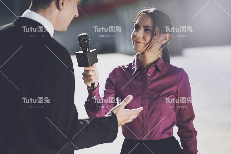 一名身穿酒红色衬衫、面带微笑的记者听着这名男子的回答