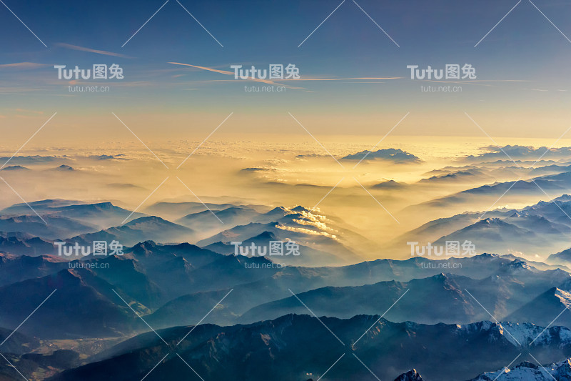 从飞机上俯瞰，透过云层从山顶俯瞰美丽的山景。