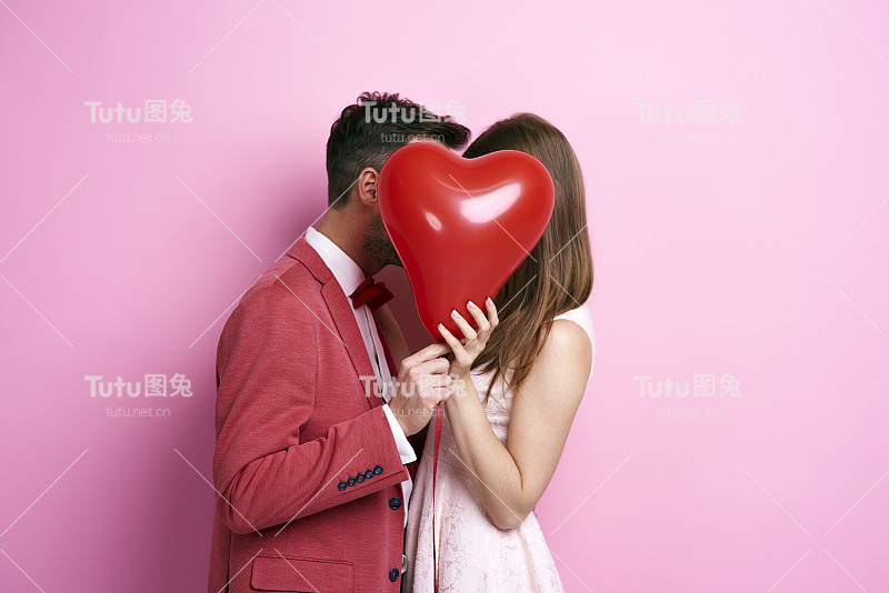 深情的夫妇用气球覆盖脸和亲吻