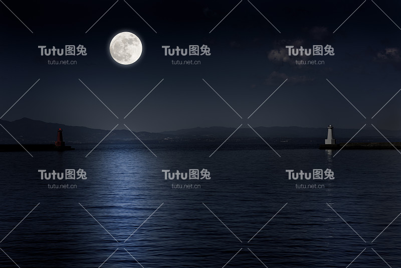 满月在海面和灯塔上升起