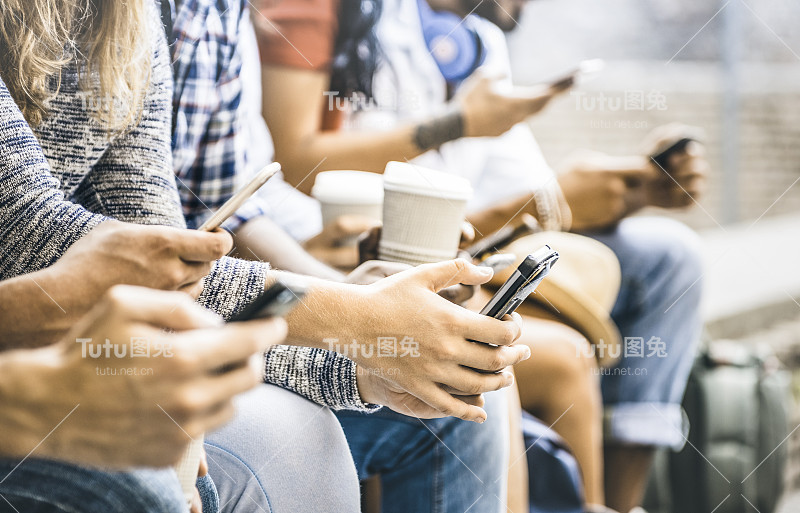 多文化的朋友群使用智能手机与咖啡在大学休息-人们的手沉迷于移动智能手机-技术概念与连接的时尚千禧一代-滤镜图像