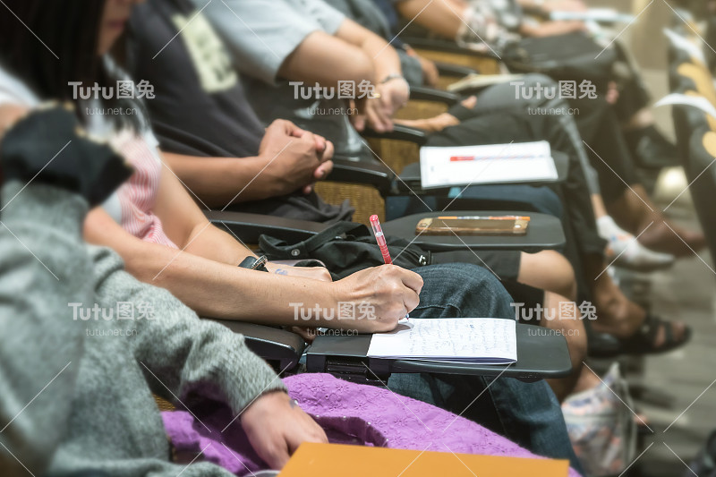 近距离拍摄女性手写在会议大厅或研讨会桌上的纸上，商业和教育理念