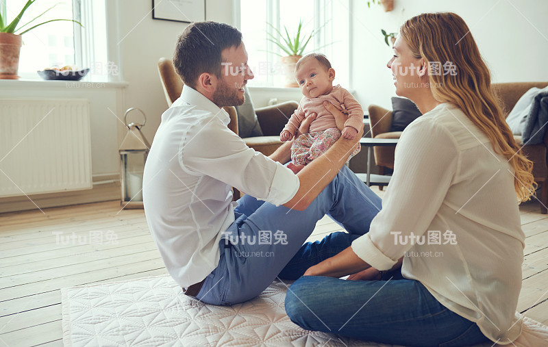 微笑的年轻父母和他们的宝贝女儿坐在家里