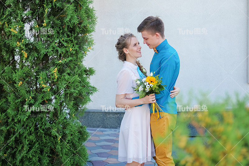 幸福的情侣在街上拥抱，笑着玩。男人和女人之间的爱情。丈夫和妻子拥抱在一起。女孩轻轻地按了一下她的男朋友。