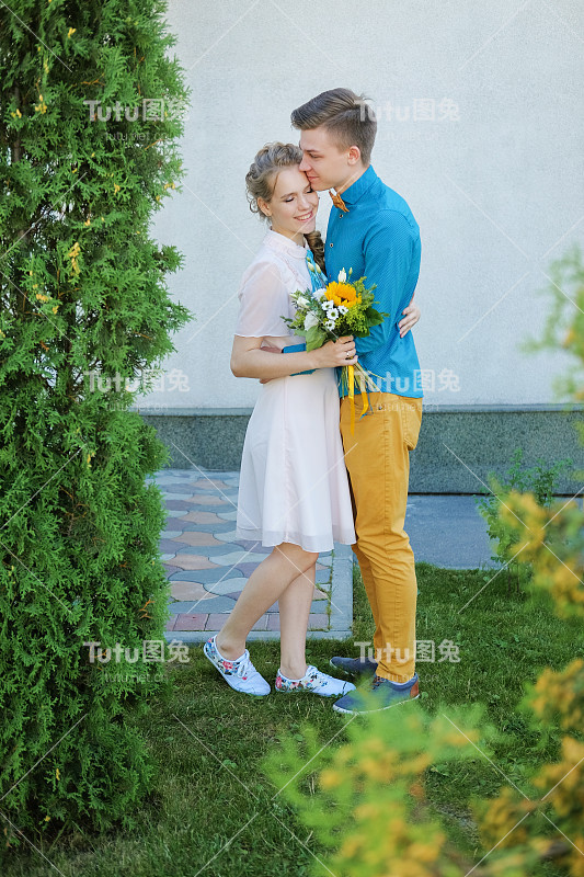 幸福的情侣在街上拥抱，笑着玩。男人和女人之间的爱情。丈夫和妻子拥抱在一起。女孩轻轻地按了一下她的男朋友。