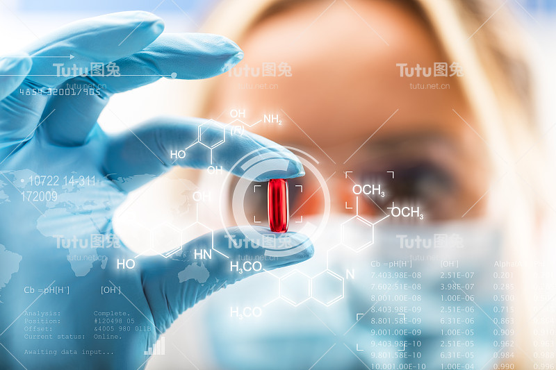 年轻迷人的女科学家拿着一颗红色透明药丸