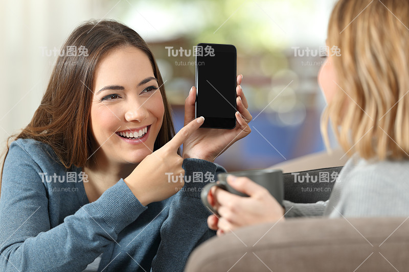 女孩在家里给朋友看一个空白的手机屏幕