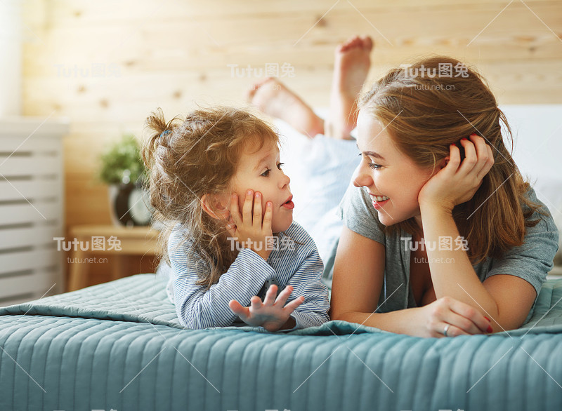 幸福的家庭妈妈和孩子女儿在床上笑