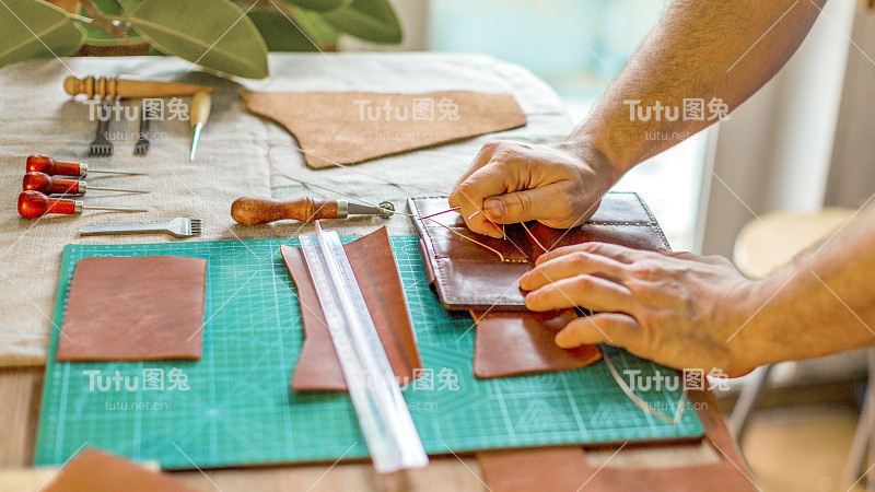 一个皮革工匠的手在一个车间与皮革纺织工作