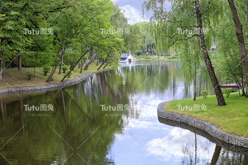 装饰池塘和浮动鸭屋与喷泉在一个美丽如画的夏季公园。