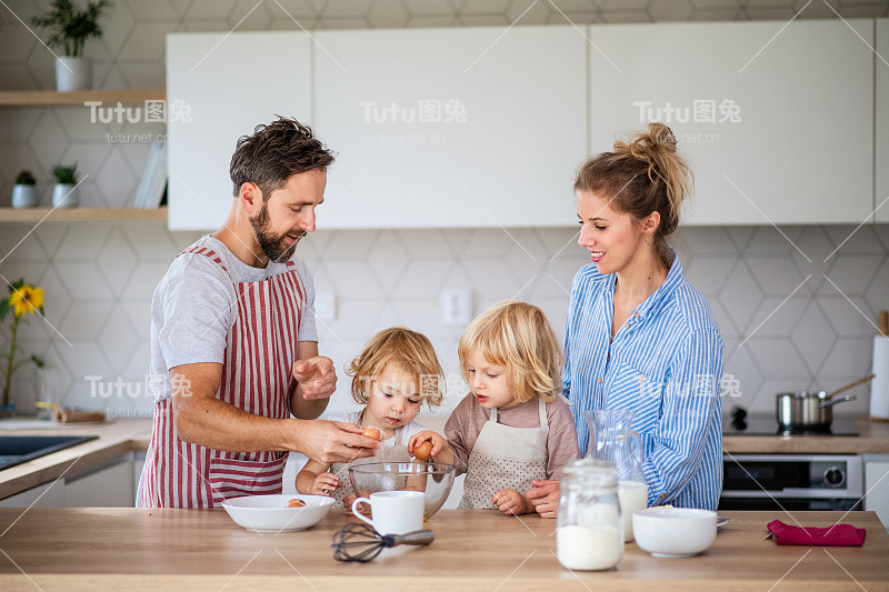 年轻的家庭和两个小孩在厨房里做饭。