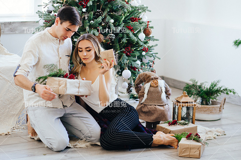 相爱的夫妇在圣诞树旁互赠礼物。