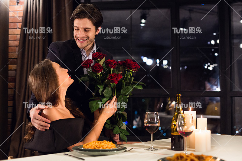 快乐的男人为他心爱的女朋友献上玫瑰花束