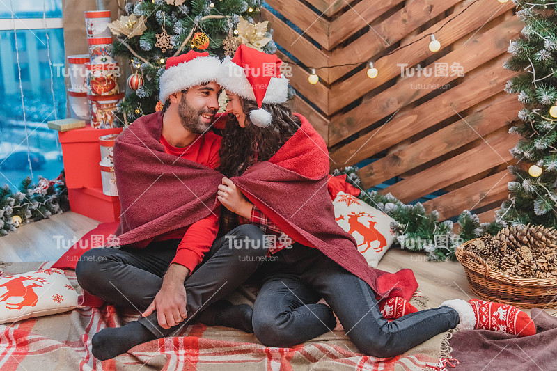 年轻的家庭一起唱圣诞颂歌在格子地毯附近的圣诞冷杉。