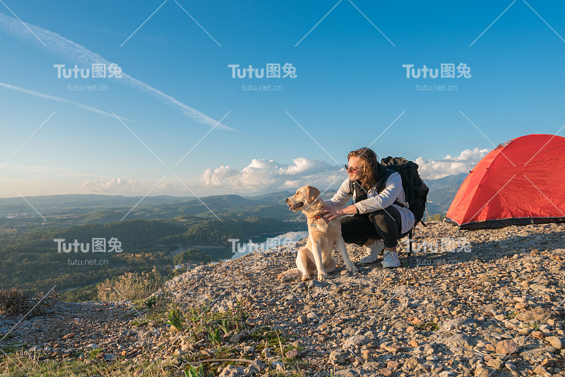 一个年轻人和她的狗在山顶露营