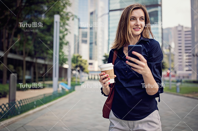 年轻的女商人一边发短信一边走向她的办公室