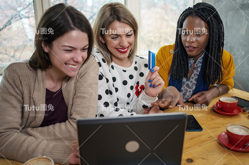 美丽的年轻女子多民族妇女在网上购物的咖啡馆