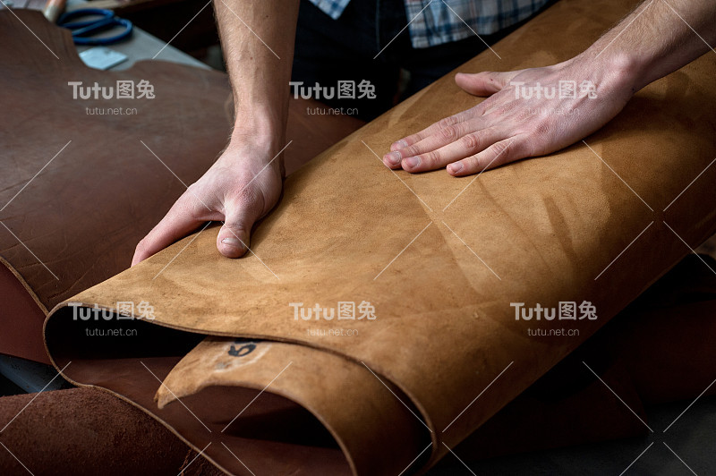 工匠的手放在皮革卷上。明暗对比的艺术、仿麂皮