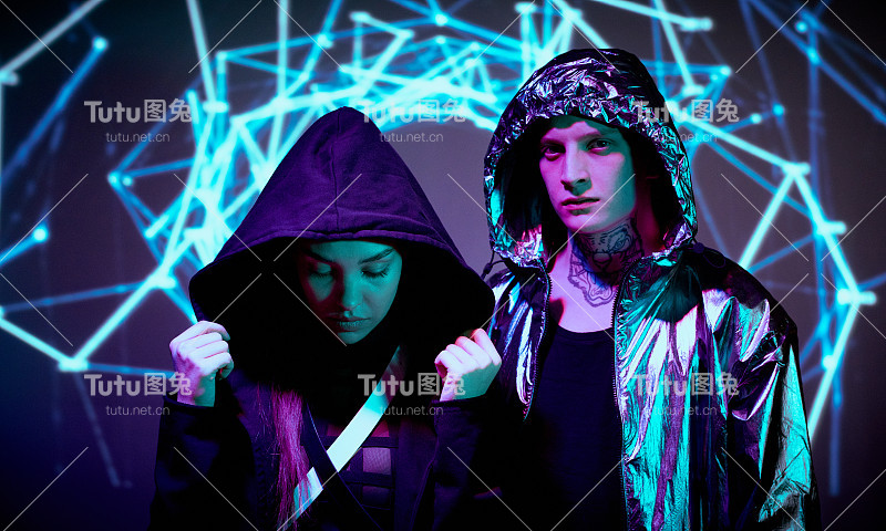 年轻女子调整兜帽，年轻男子在脖子上纹身看着摄像头，网络环境的明亮字符