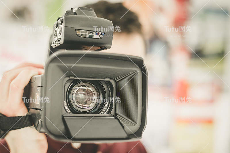 专业电影制作:男性电影人正在用专业的电影摄影机进行拍摄。相机镜头的特写。