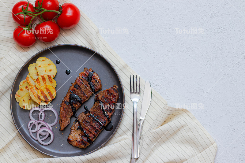 西红柿猪肉排。猪肉牛排在家庭食品概念上的灰色背景俯视图。餐厅的菜单设计。