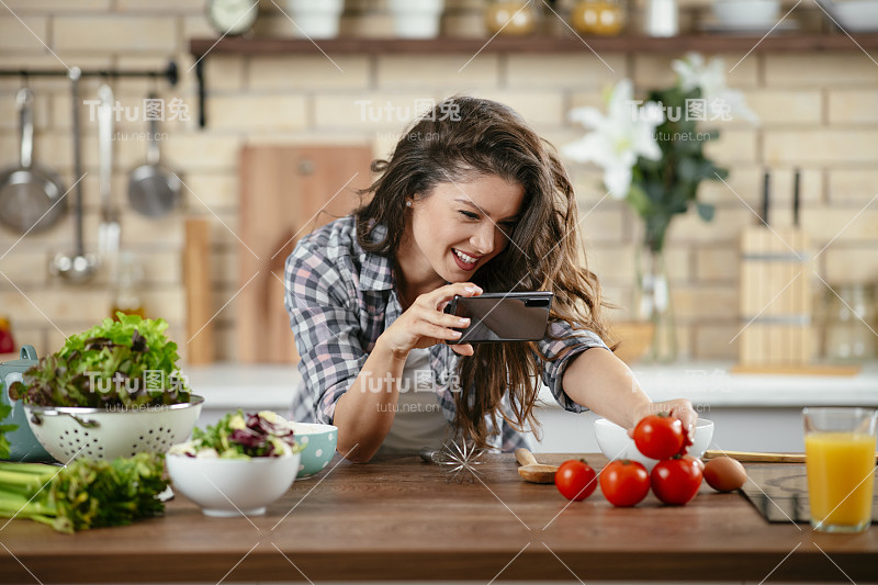 一个年轻女子在厨房里拍摄食物。