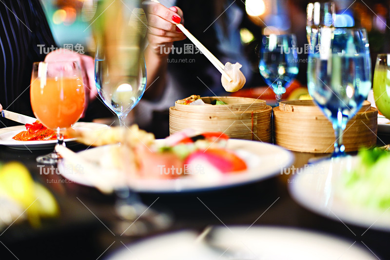 中餐馆里，女士手里拿着筷子和饺子，桌子摆好。