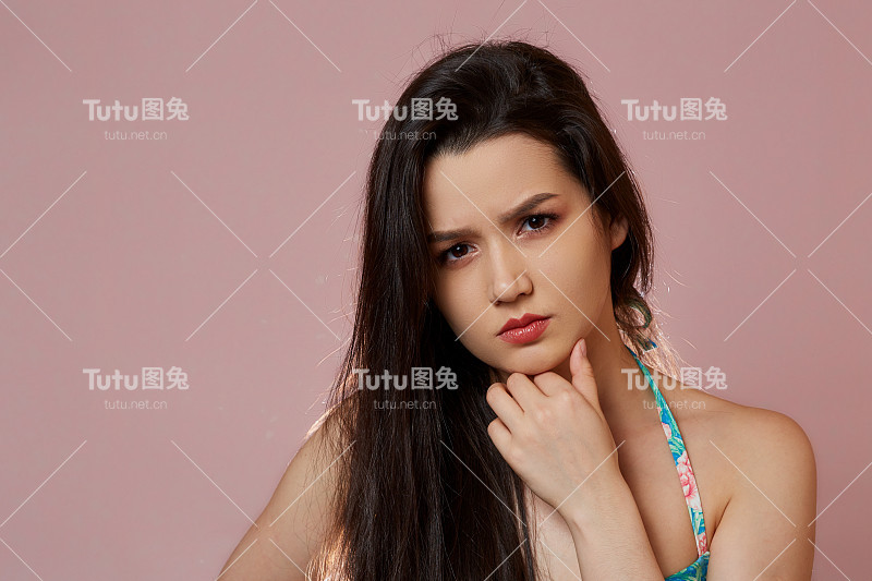 一个年轻美丽苗条的亚洲女孩穿着蓝色泳衣在粉红色的孤立的背景下思考