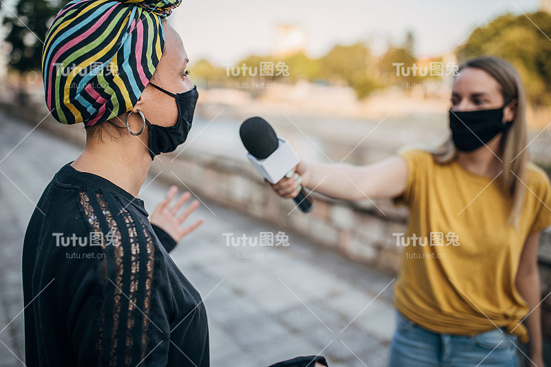 2019冠状病毒大流行期间，在街头接受女记者采访的妇女