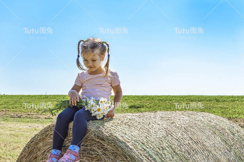草堆上戴着雏菊的小女孩