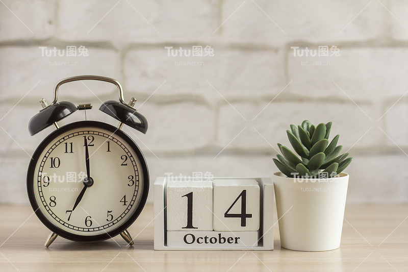 10月14日在闹钟旁边的木制日历上，是秋季月份的日期