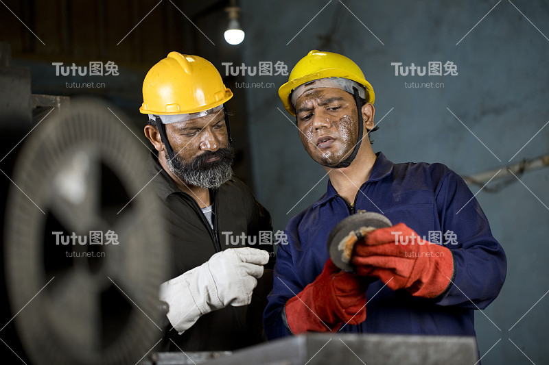 两名机械师在工厂检查金属产品的精加工