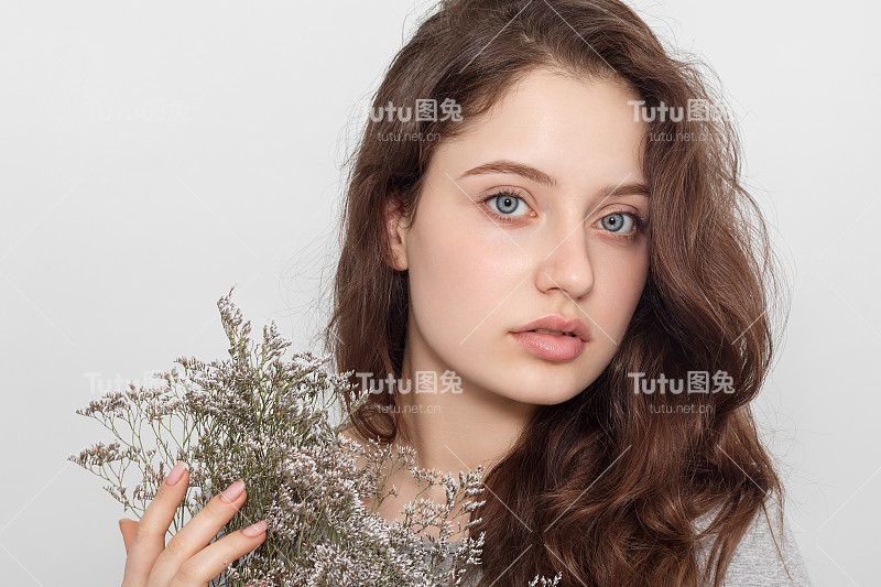 美丽少女捧着一束野花，画像。长长的头发和大大的蓝眼睛。