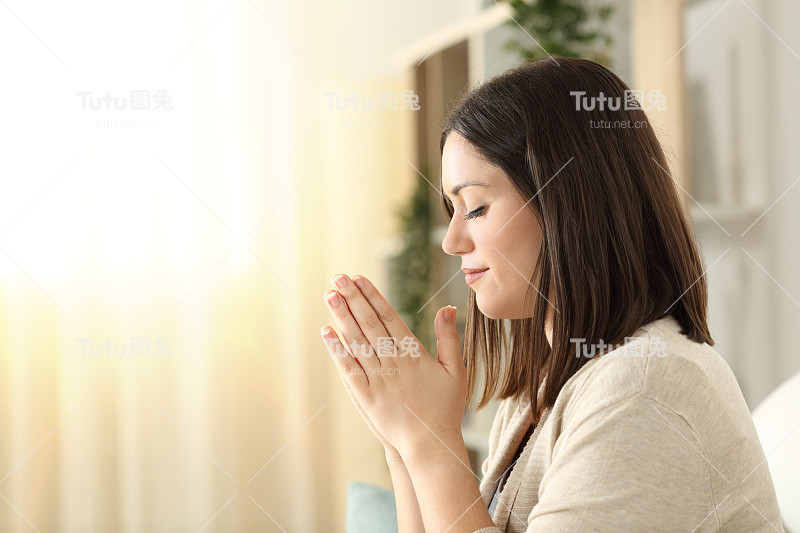一个在家祈祷的女人的侧面图