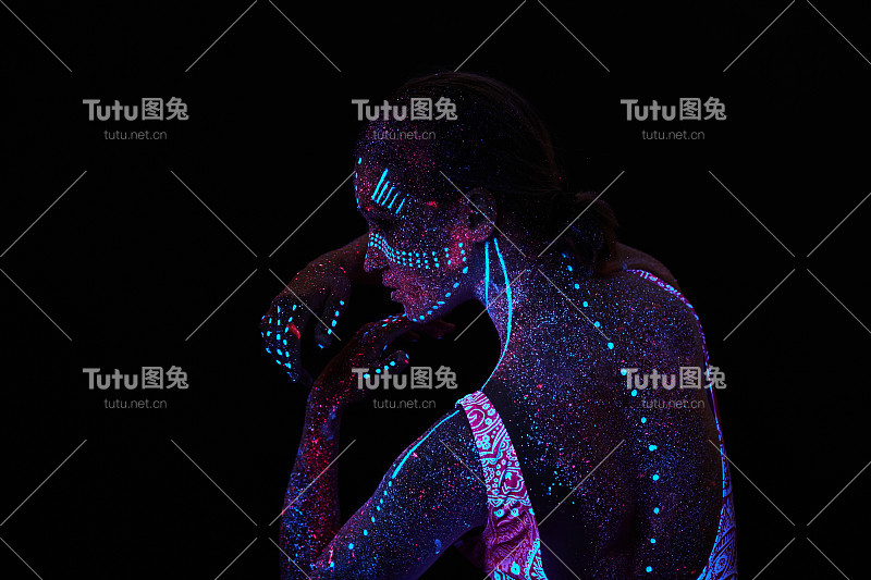 女人做瑜伽，手部运动，热身运动。紫外线下的艺术女孩宇宙。全身覆盖着彩色的水滴。星体瑜伽。噪音，焦点模糊