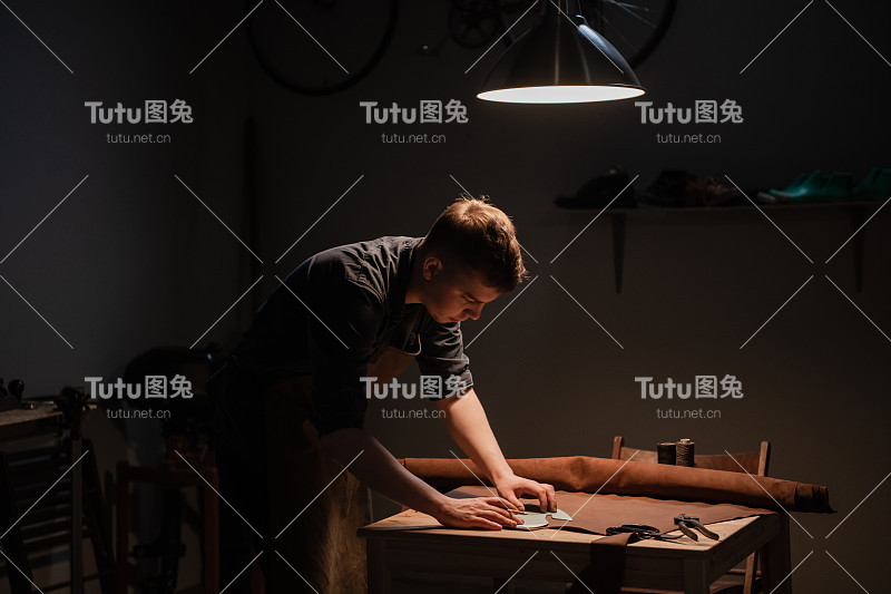 一位世袭的鞋匠在家庭作坊里用皮革做鞋