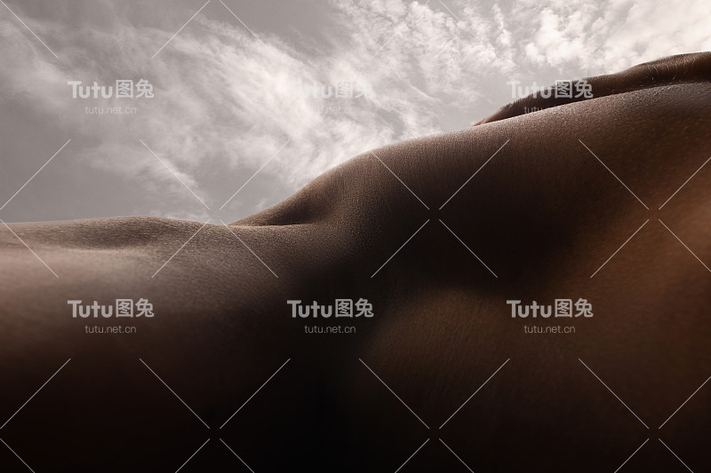 详细的人体皮肤纹理。近距离拍摄年轻的非洲裔美国男性身体像风景与天空的背景