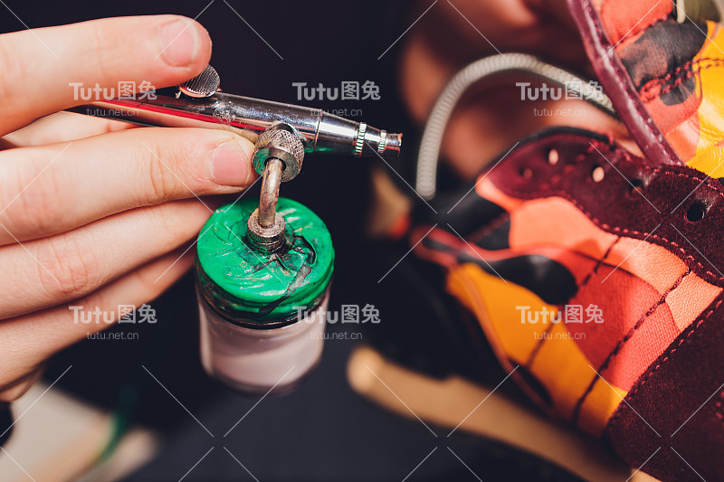 工匠画在一双鞋上。粉刷和修复绒面革运动鞋。