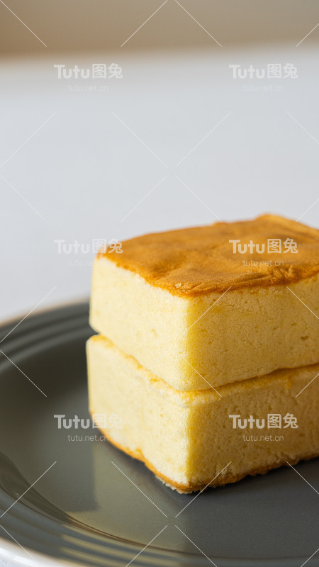 方形的松软的蛋松糕放在一个黑色的盘子里，早餐糕点，垂直的形象