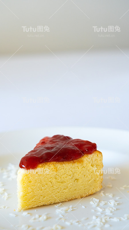 三角形的海绵蛋糕在盘子里，红果酱在蛋糕上，白色的背景与复制空间